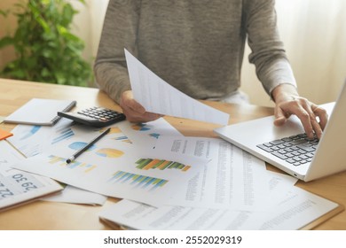 Accountant Analyzing Business Charts And Financial Reports To Illustrate Stock Market Growth And Marketing Strategies In Professional Office Or Home Work Environments. - Powered by Shutterstock