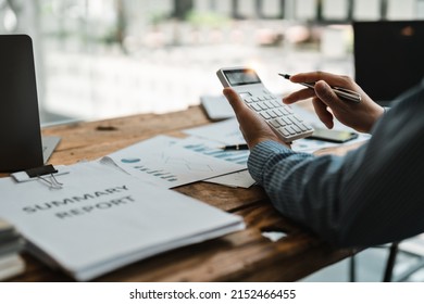 Accountant Or Bookkeeper Working With Calculator To Calculate Business Data Summary Report, Accountancy Document And Laptop Computer At Office, Business Concept