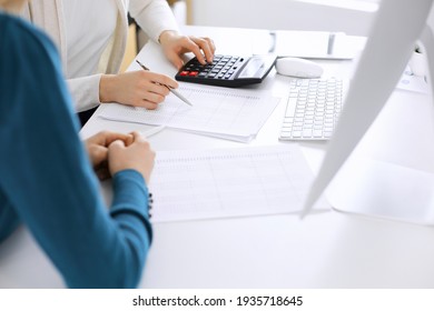 Accountant checking financial statement or counting by calculator income for tax form, hands close-up. Business woman sitting and working with colleague at the desk in office. Audit concept - Shutterstock ID 1935718645