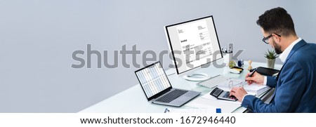 Accountant Making Invoice On Computer At Desk