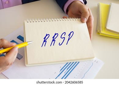 Accountant Shows To The Sign RRSP Registered Retirement Savings Plan Sign On The Jotter. 
