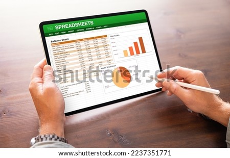 Accountant viewing financial data spreadsheets on the screen of tablet computer