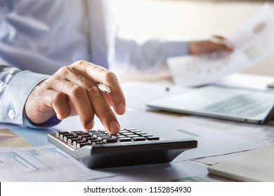 Accountant Working On Desk Using Calculator For Calculate Finance Report In Office