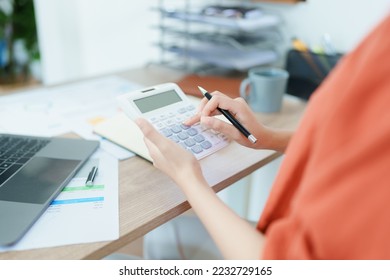 Accountants, Asian auditors are using calculators and computers to review annual tax budgets to submit information to the IRS - Shutterstock ID 2232729165