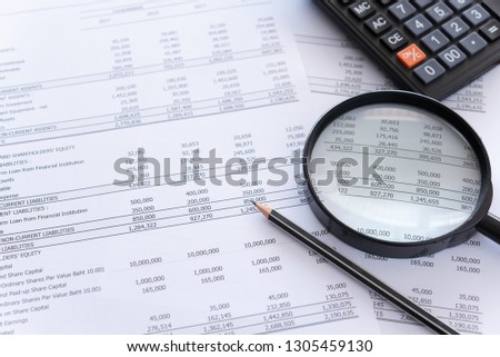 accounting audit concept. calculator and magnifying glass on financial statement and balance sheet annual on auditor's desk.