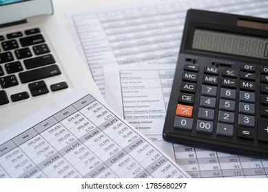 Accounting business concept. Calculator with accounting report and financial statement with laptop computer on desk.
