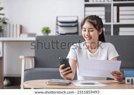 Accounting. Focused young asian female sit on sofa pay domestic bills fees online using phone count amount payable on digital calculator. woman plan monthly budget at home office