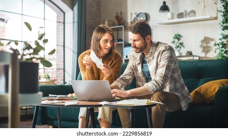 Accounting at Home: Couple Using Laptop Computer, Consulting Eachother in Apartment. Young Family Filling Tax Forms, Mortgage Documents, Bills, Checks, Balances, Invoices are in Order - Powered by Shutterstock