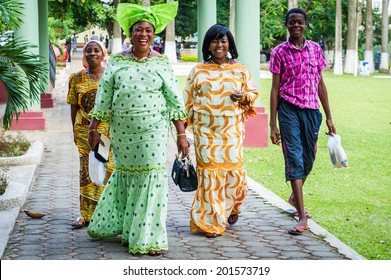 ACCRA, GHANA - MARCH 3, 2012: Unidentified Ghanaian women walk on the grass in bright dresses in the street in Ghana. People of Ghana suffer of poverty due to the unstable economic situation
