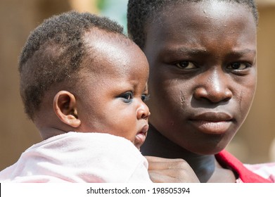 ACCRA, GHANA - MARCH 6, 2012: Unidentified Ghanaian mother carries her little baby on her arms in the street in Ghana. Children of Ghana suffer of poverty due to the unstable economic situation