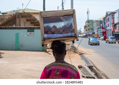 ACCRA, GHANA – September 23, 2020: A Trader Walks With Food On Her Head For Sale. Informal Economy Ghana.