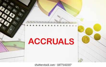 Accruals on notepad with calculator, coins, graphicson financial report. Business and financial concept