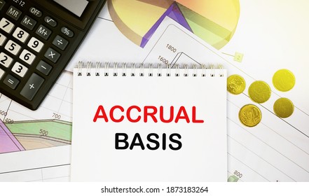 Accural basis on notepad with calculator, coins, graphics on financial report. Business and financial concept