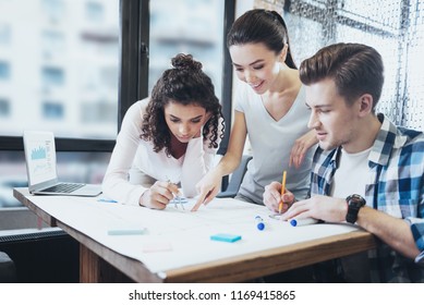 Accurate Planning. Appealing Three Architects Leaning Over Blueprint While Looking Down