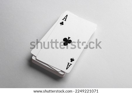 Ace of clubs on a stack of playing cards, gray background