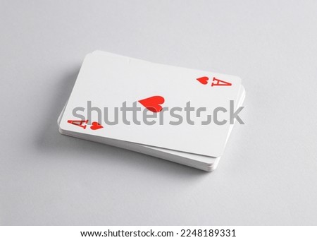 Ace of hearts on top of stack of playing cards, gray background