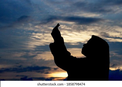 Aceh, Indonesia - July 14, 2020: Silhouette of a person praying with their hands raised in the afternoon