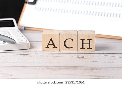 ACH Automated Clearing House word on wooden block with clipboard and calcuator - Shutterstock ID 2353171061