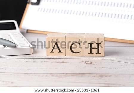 ACH Automated Clearing House word on wooden block with clipboard and calcuator