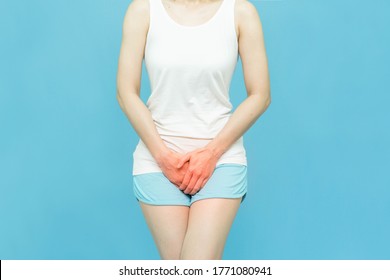 Ache concept ,woman holding the crotch because Itching or urinary, painful illness feeling unwell,wearing white undershirt standing over isolated blue background