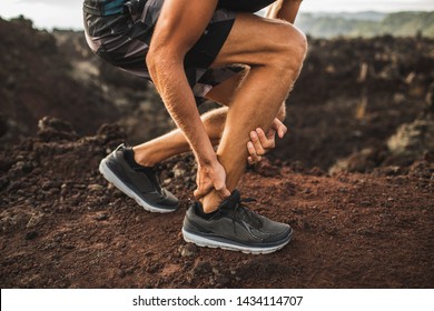 Achilles injury on running outdoors. Man holding Achilles tendon by hands close-up and suffering with pain. Sprain ligament or Achilles tendonitis.