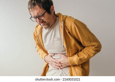 Aching Stomach Pain, Man Pressing The Lower Abdomen Of His Body With Painful Grimace And Gastroenteritis Symptoms.