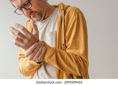 Aching Wrist Pain As Symptom Of Tendonitis Or Arthritis, Adult Caucasian Male With Painful Grimace Looking Down At His Joint