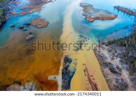 Acid rivers flowing from an industrial copper mine pollute the environment. Orange soil is contaminated with heavy metals from an industrial plant. Aerial view from drone