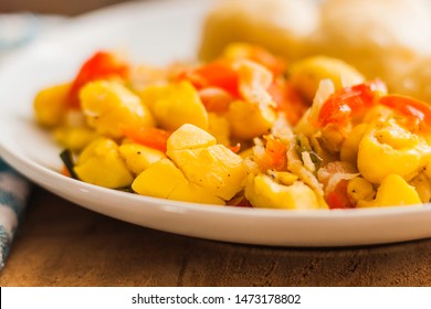 Ackee and Salt fish served with fried dumplings and served on a white plate