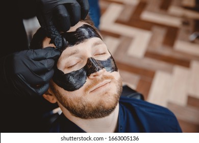 Acne Removal With Cosmetic Product, Cleaning Pores Of Men Skin, Barber Applying Black Charcoal Mask To Client Man In Spa Salon.