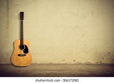 Acoustic guitar is against old style wall.