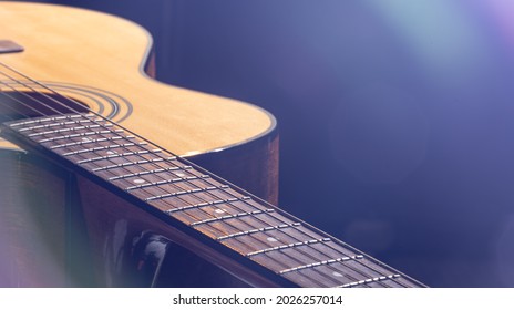 Acoustic guitar with a beautiful wood on a black background in the light of a spotlight.