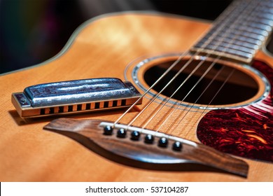 Acoustic guitar with country blues harmonica ready on stage