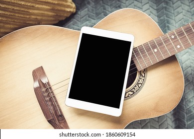 Acoustic guitar and digital tablet on a couch at cozy home background. Online music lessons, learning playing or writing songs and hobby concept. Top view, flat lay, mock up - Powered by Shutterstock
