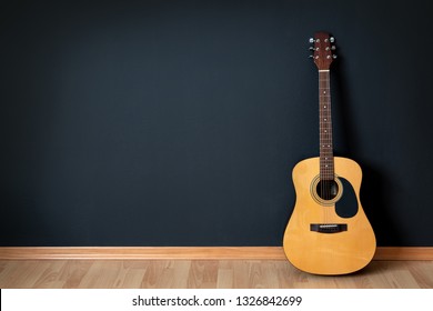 Acoustic guitar leaning on black wall - Powered by Shutterstock