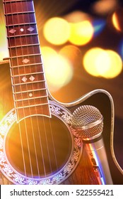 Acoustic Guitar And Microphone With Lights In The Background. Country Or Bluegrass Concert Concept. Front View. Horizontal Composition.