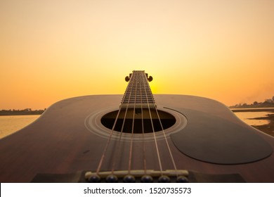 Acoustic guitar on the beach against sunset  - Powered by Shutterstock
