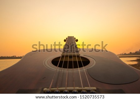 Acoustic guitar on the beach against sunset 