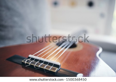 Acoustic guitar on a living room couch / sofa.