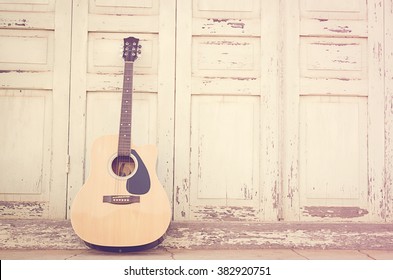 Acoustic guitar on old wooden door background 