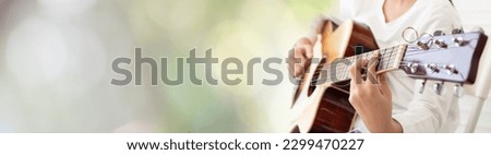 Acoustic guitar player banner for webpage. Young girl guitarist put fingers on fingerboard of wooden guitar play fingerpicking melody isolated on blurry background. copy space.