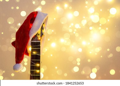 Acoustic Guitar with red Santa hat and light garland with bokeh. Christmas music song concept with copyspace on white background - Powered by Shutterstock