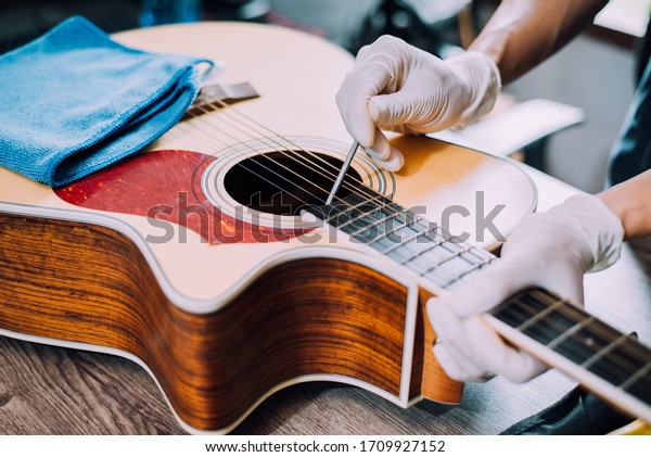 Acoustic guitar repairman, Screw the guitar\
neck, Close-up.