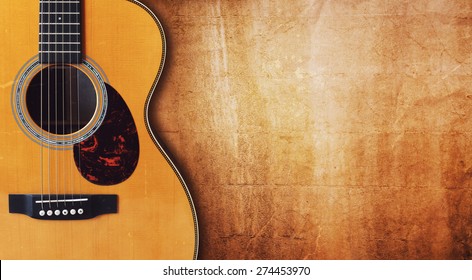 Acoustic guitar resting against a blank grunge background with copy space
