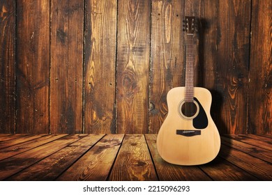 Acoustic guitar resting against a wall background