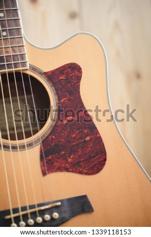 Acoustic guitar resting against a wooden background with copy space