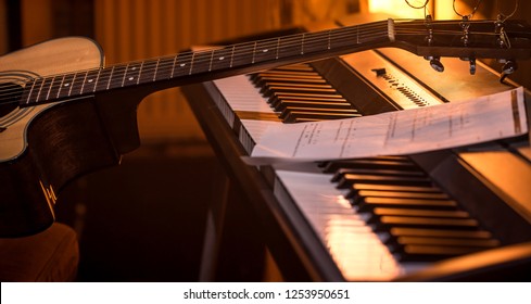 acoustic guitar stands on piano with notes, close-up, beautiful color background, music activity concept - Powered by Shutterstock
