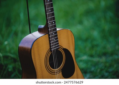 Acoustic guitar, stringed musical instrument, placed in the grass, classical guitar, playing music and relaxing. - Powered by Shutterstock