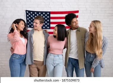 Acquaintance And First Day In Language Courses Or Student Exchange. Happy Young International People Look At Each Other, On White Brick Wall Background With Big USA Flag, Copy Space, Studio Shot