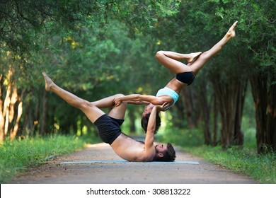 Acro yoga, two sporty people practice yoga in pair, couple doing stretching exercise in the garden - Powered by Shutterstock
